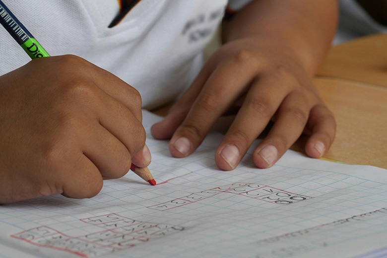 Child writing in a book with a pencil