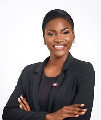 Smiling Black woman with dark hair pulled back neatly, wearing a black blazer with arms crossed against a plain white background