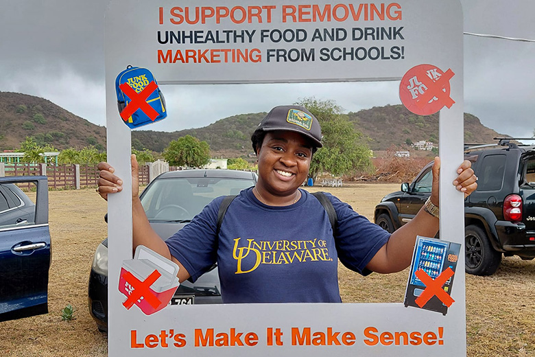 Woman holding a cutout sign reading: I support removing unhealthy food and drink marketing from schools! Let's Make It Make Sense!